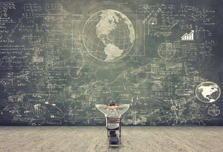 Homme assis devant un tableau géant avec des calculs et formules mathématiques